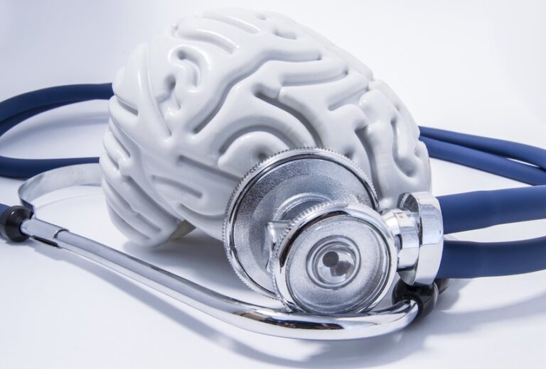 A white anatomical brain model with a blue stethoscope representing medical diagnosis and treatment of traumatic brain injuries in North Carolina.