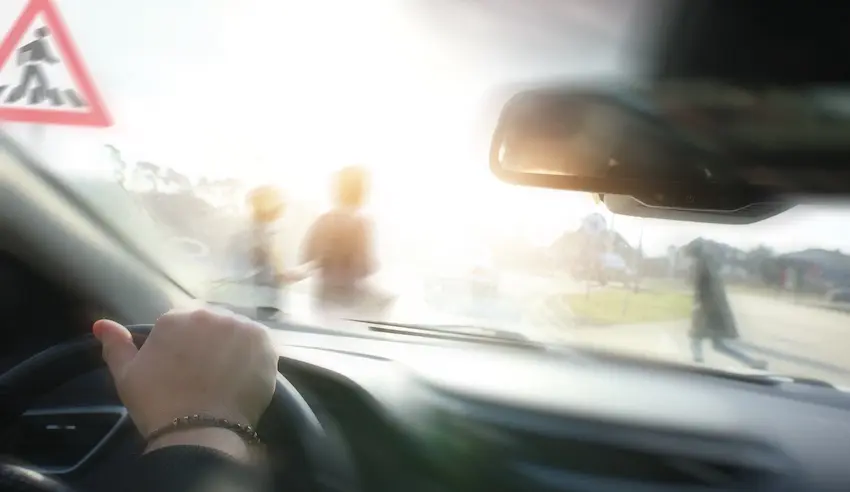 A driver's view through the windshield shows blurred pedestrians crossing the street which highlights pedestrian accident risks and safety concerns in North Carolina.