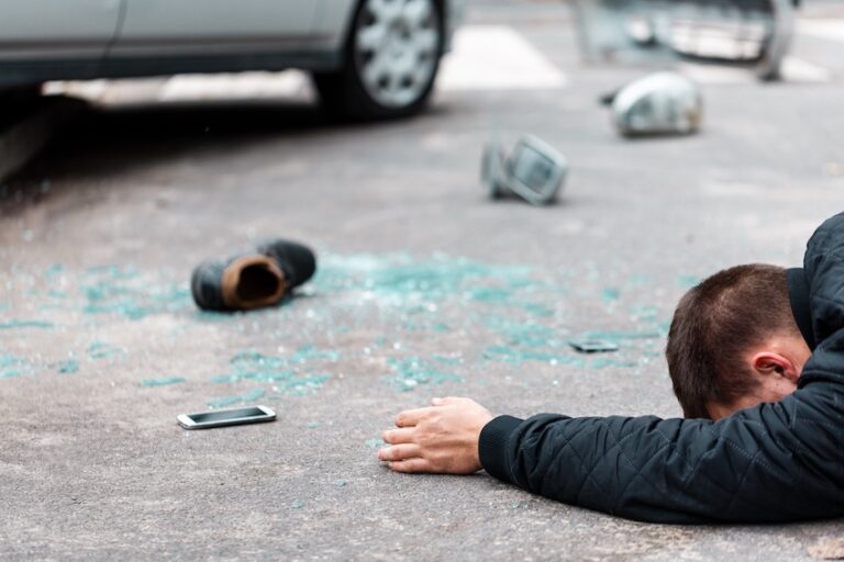 An unconscious injured man is lying on the pavement surrounded by shattered glass and debris after a pedestrian accident collision in North Carolina.