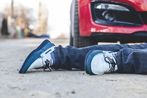 A young man hit by a car is lying on the road after a pedestrian accident.