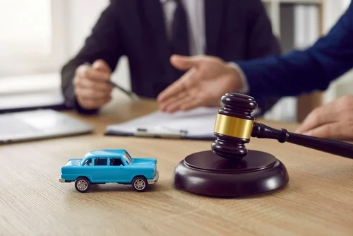 Lawyer dealing with the insurance company after a car accident, two men with a toy car and a judge’s gavel