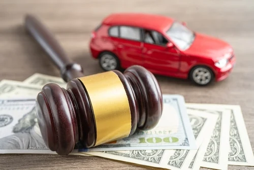 Car accident compensation or car accident settlement represented by model car, judge’s gavel, and money
